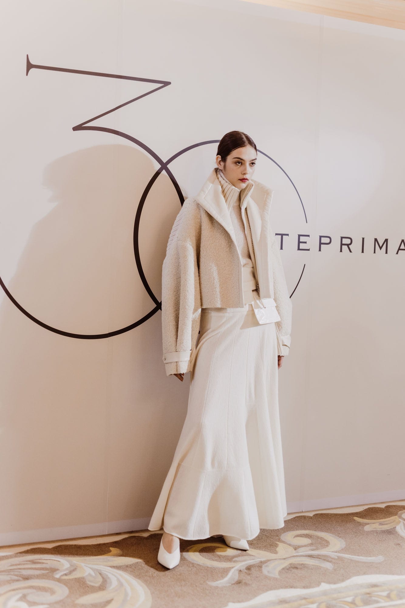 Model in a pale Anteprima look against the anniversary presentation wall