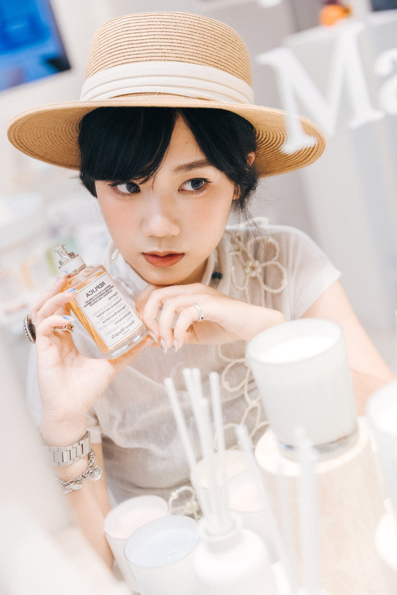 Guest holding Maison Margiela fragrance in a sun hat