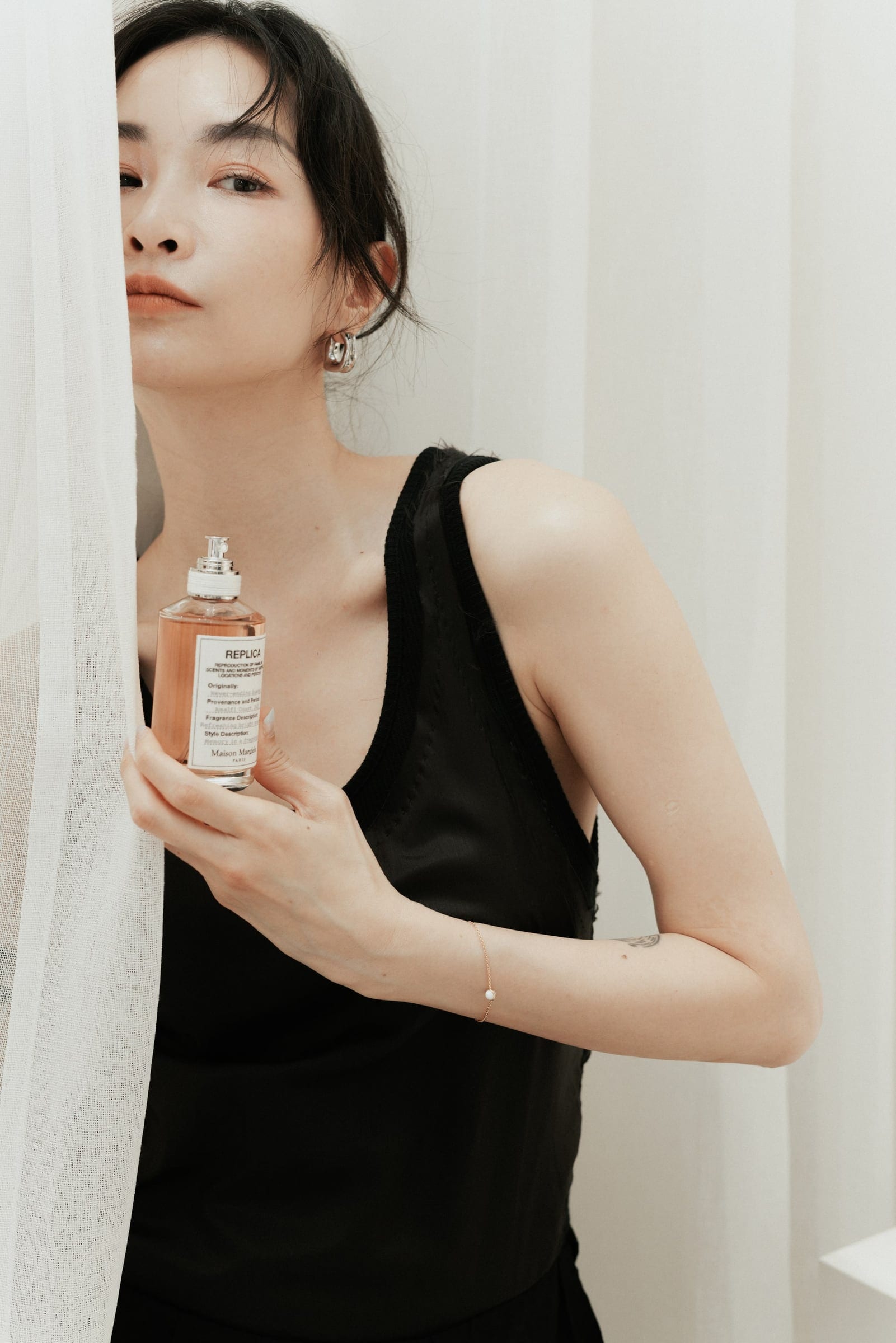 Guest holding Maison Margiela fragrance beside a curtain