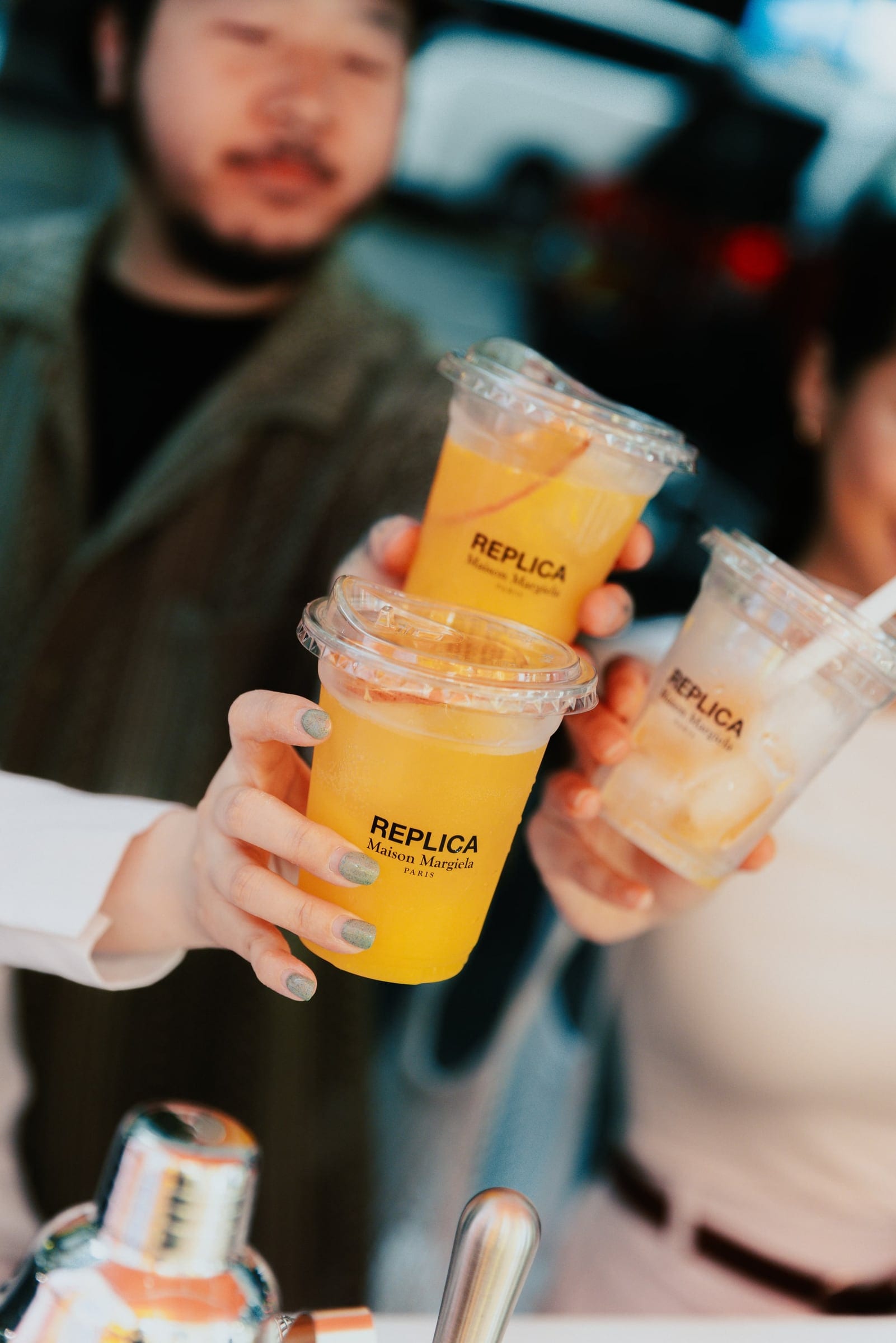 Guests holding citrus drinks at the Maison Margiela launch