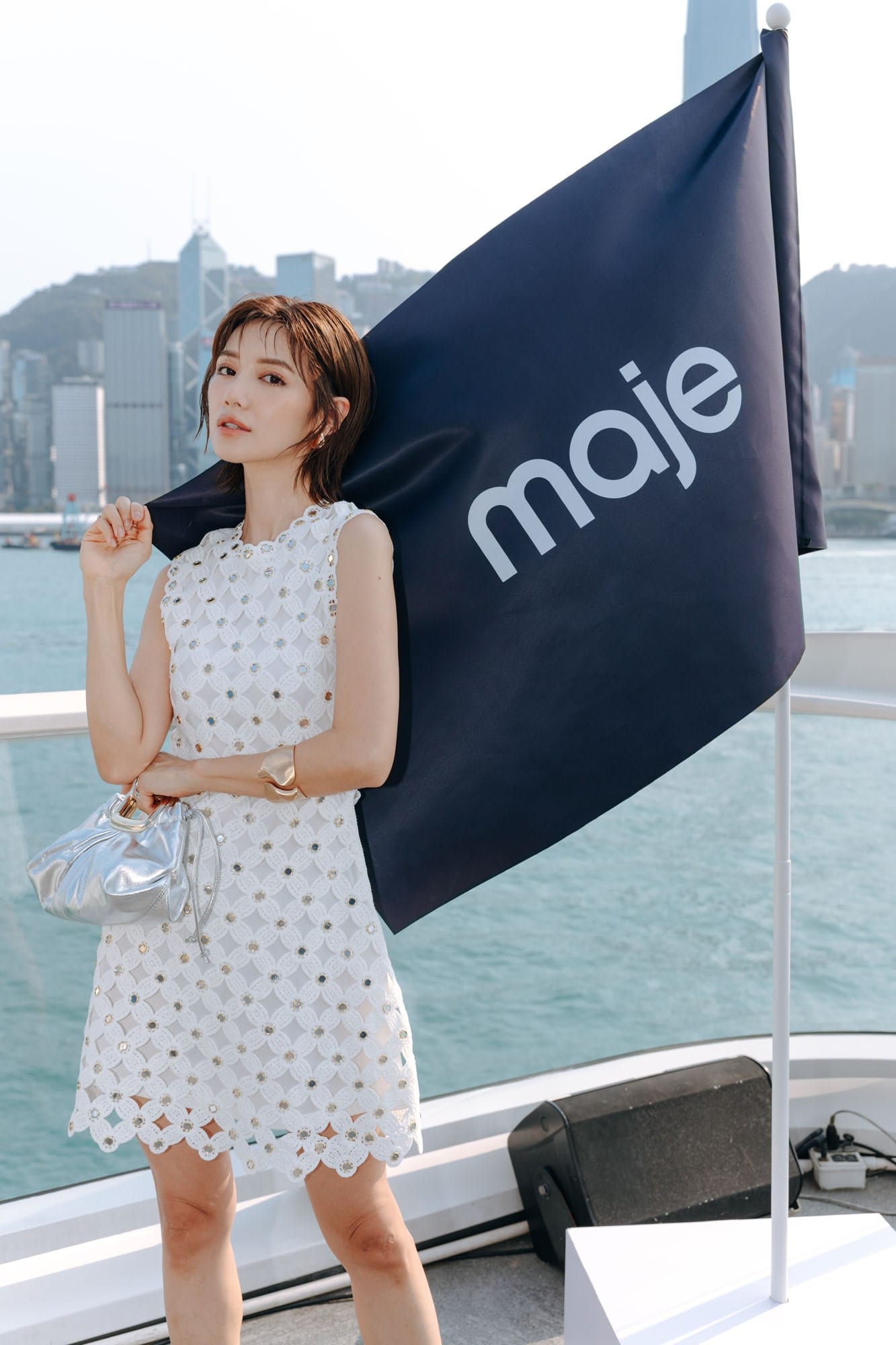 Guest in a white Maje look with a Maje flag