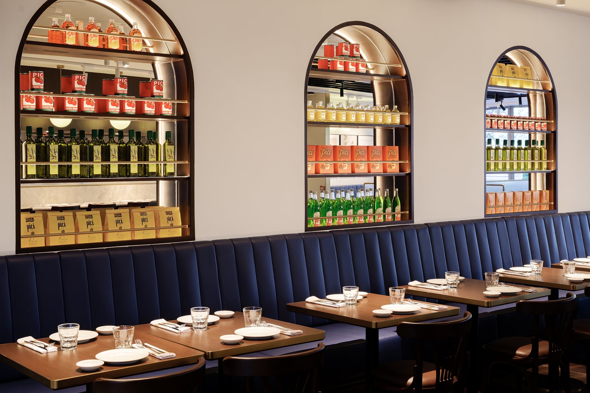 Pici restaurant interior with illuminated product shelves and banquette seating