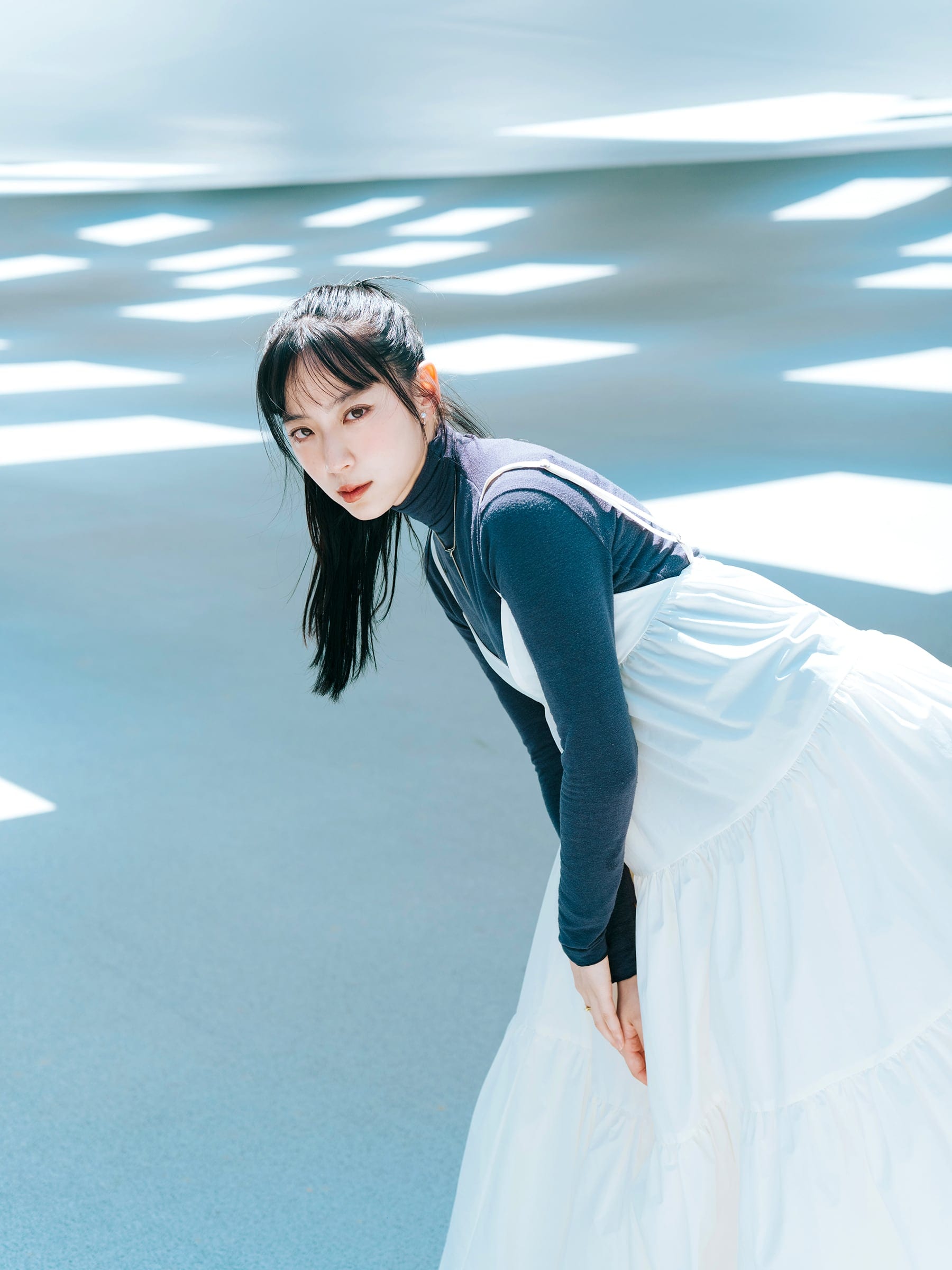 Hiyori in a white dress beneath geometric light