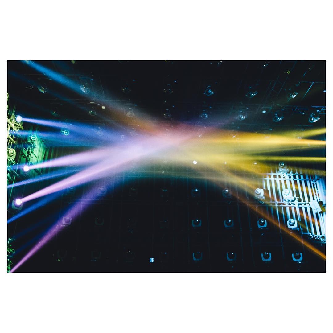 Coloured stage lights crossing a dark performance space