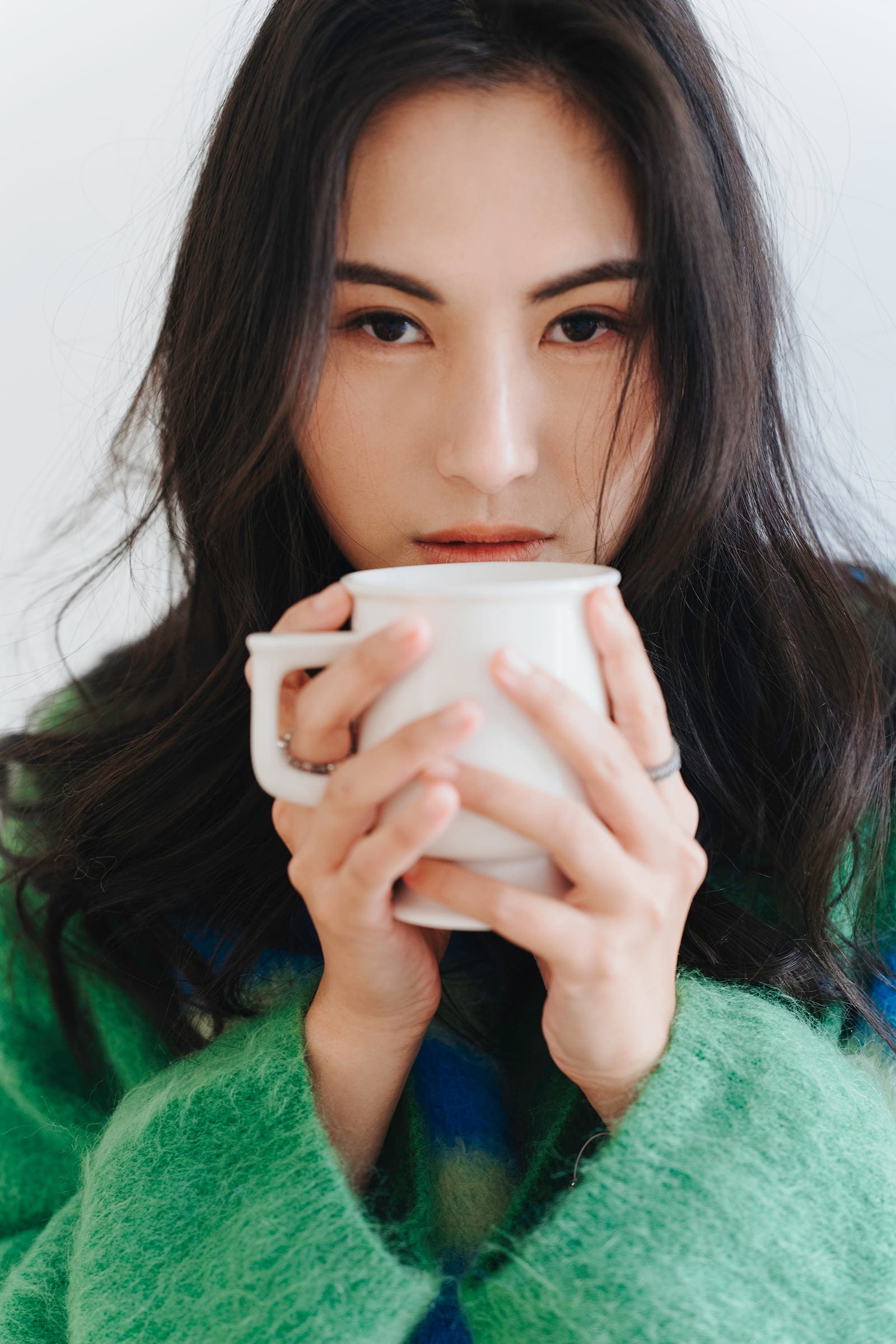 Sarah holding a white cup in a green textured setting